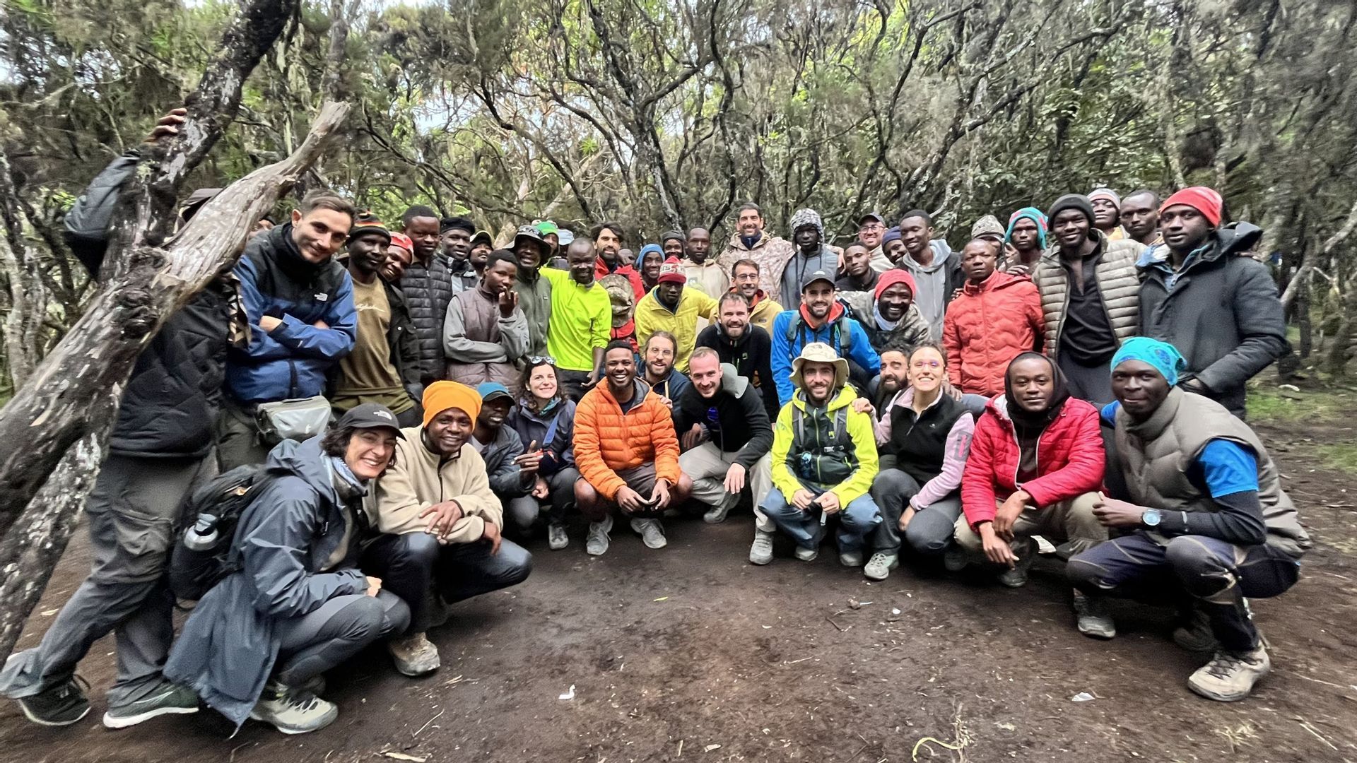 Un grande gruppo WeRoad in posa per una foto in una radura nel bosco, con abbigliamento da trekking.