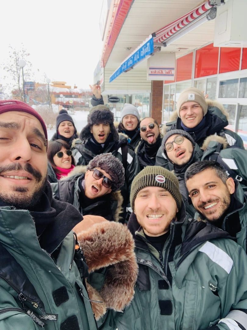 Un gruppo WeRoad in viaggio si fa un selfie, indossando caldi abiti invernali in un paesaggio innevato.
