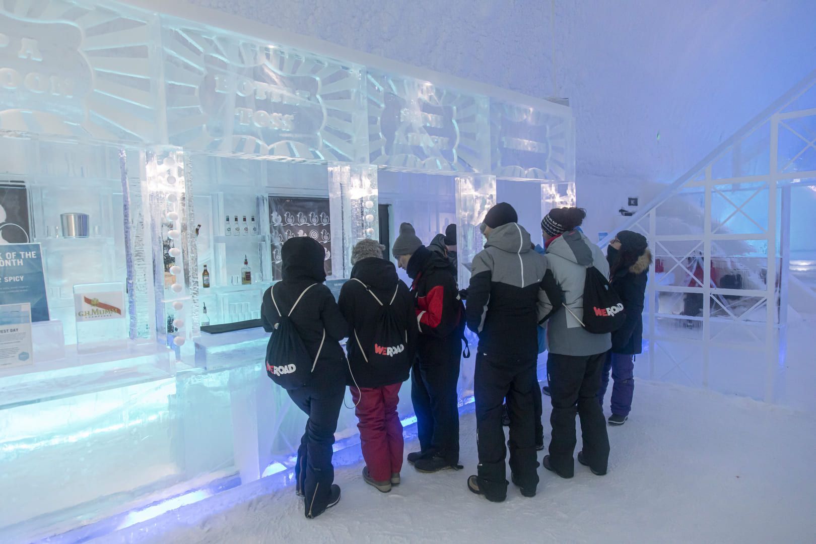 Un grupo de WeRoad con chaquetas de invierno está en la barra de un bar hecho completamente de hielo.