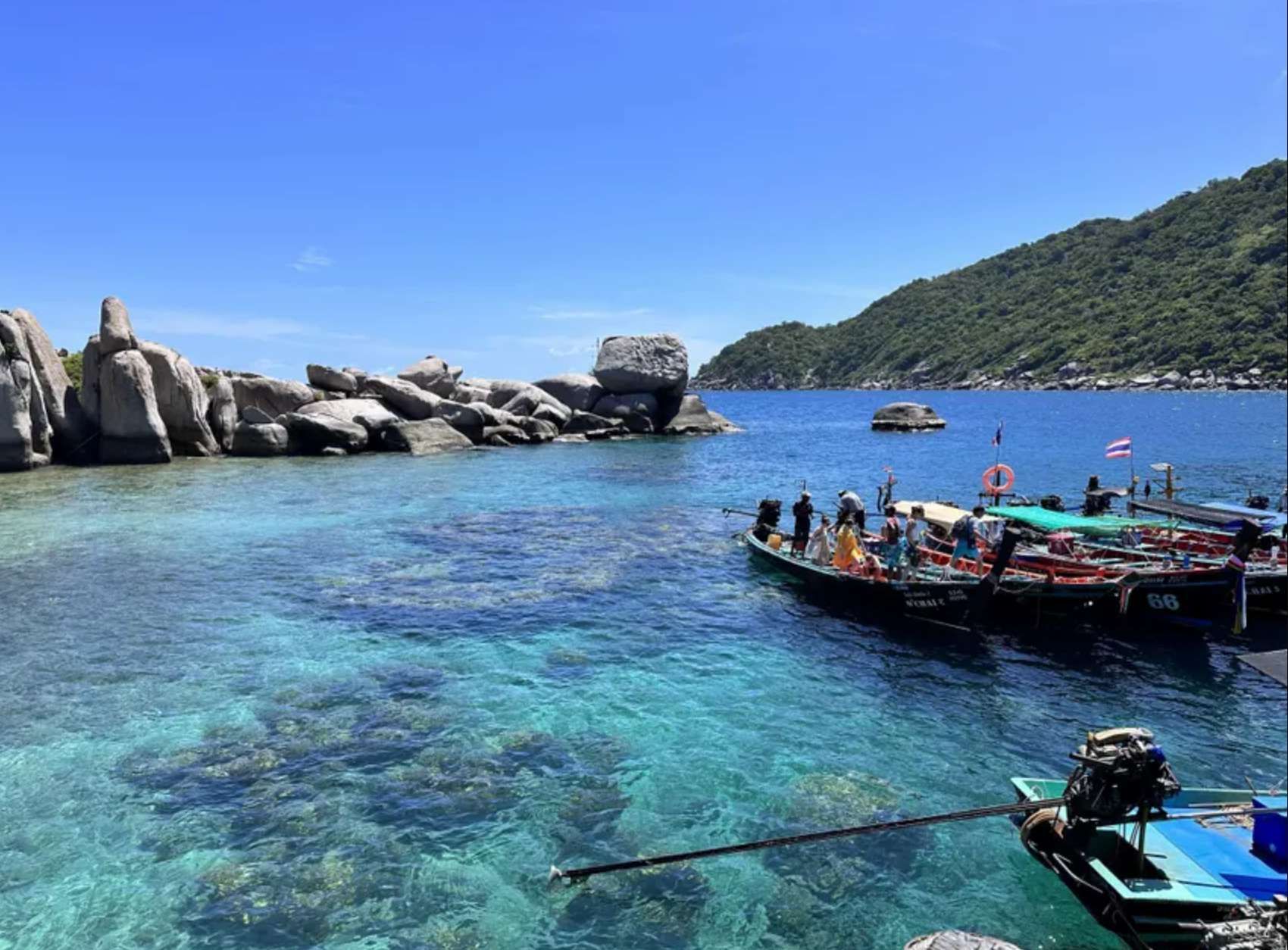 Un voyage de groupe WeRoad en bateaux à longue queue dans une baie tropicale aux eaux turquoise claires et aux grands rochers.