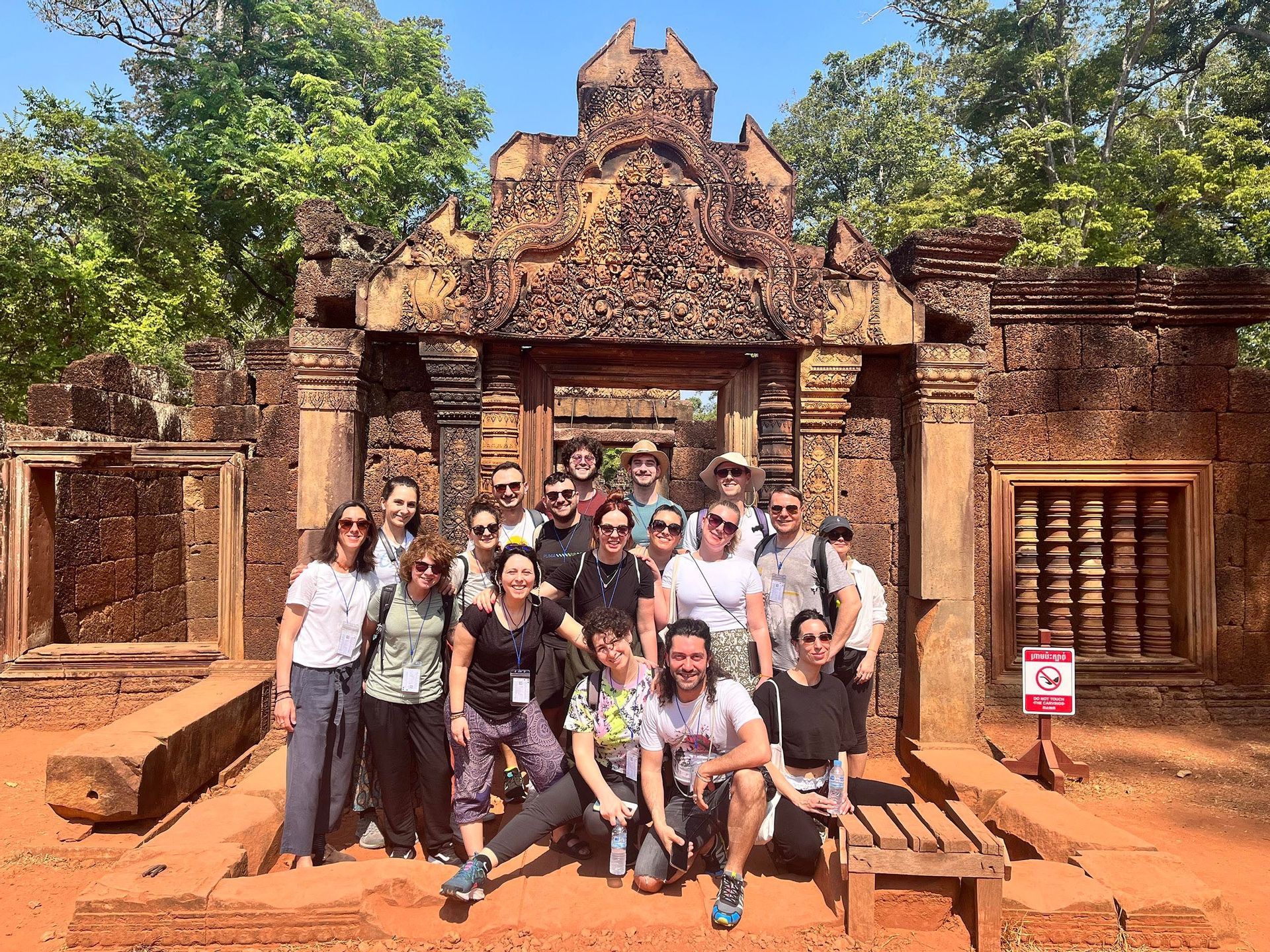 Un viaggio di gruppo WeRoad in posa per una foto davanti a un antico ingresso di tempio in pietra, riccamente scolpito.