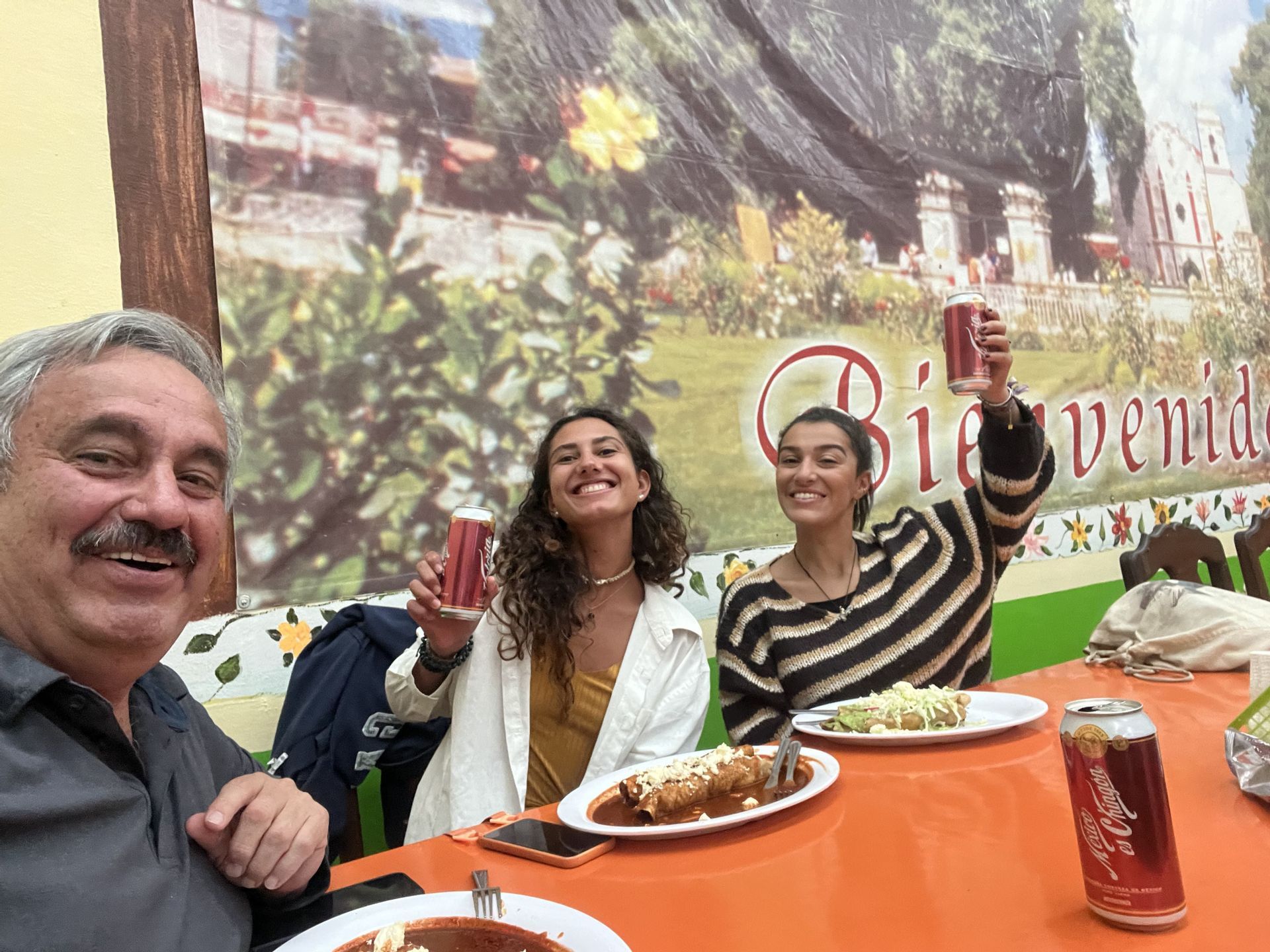 Voyage de groupe WeRoad: trois personnes souriantes trinquent et mangent au restaurant.