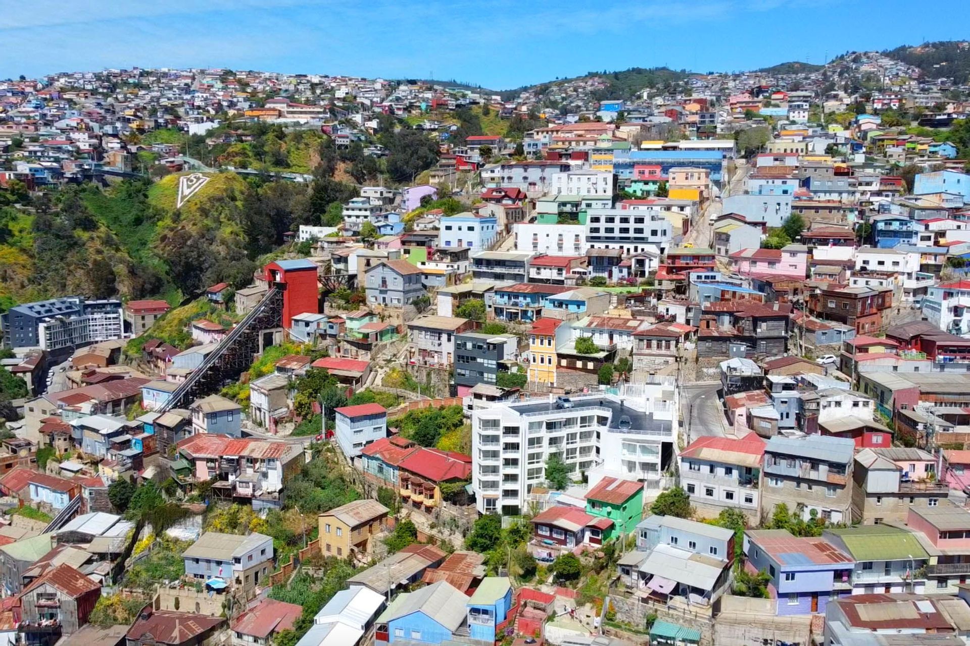 Una vista aerea di una città colorata costruita su una ripida collina, con una funicolare che sale il pendio.
