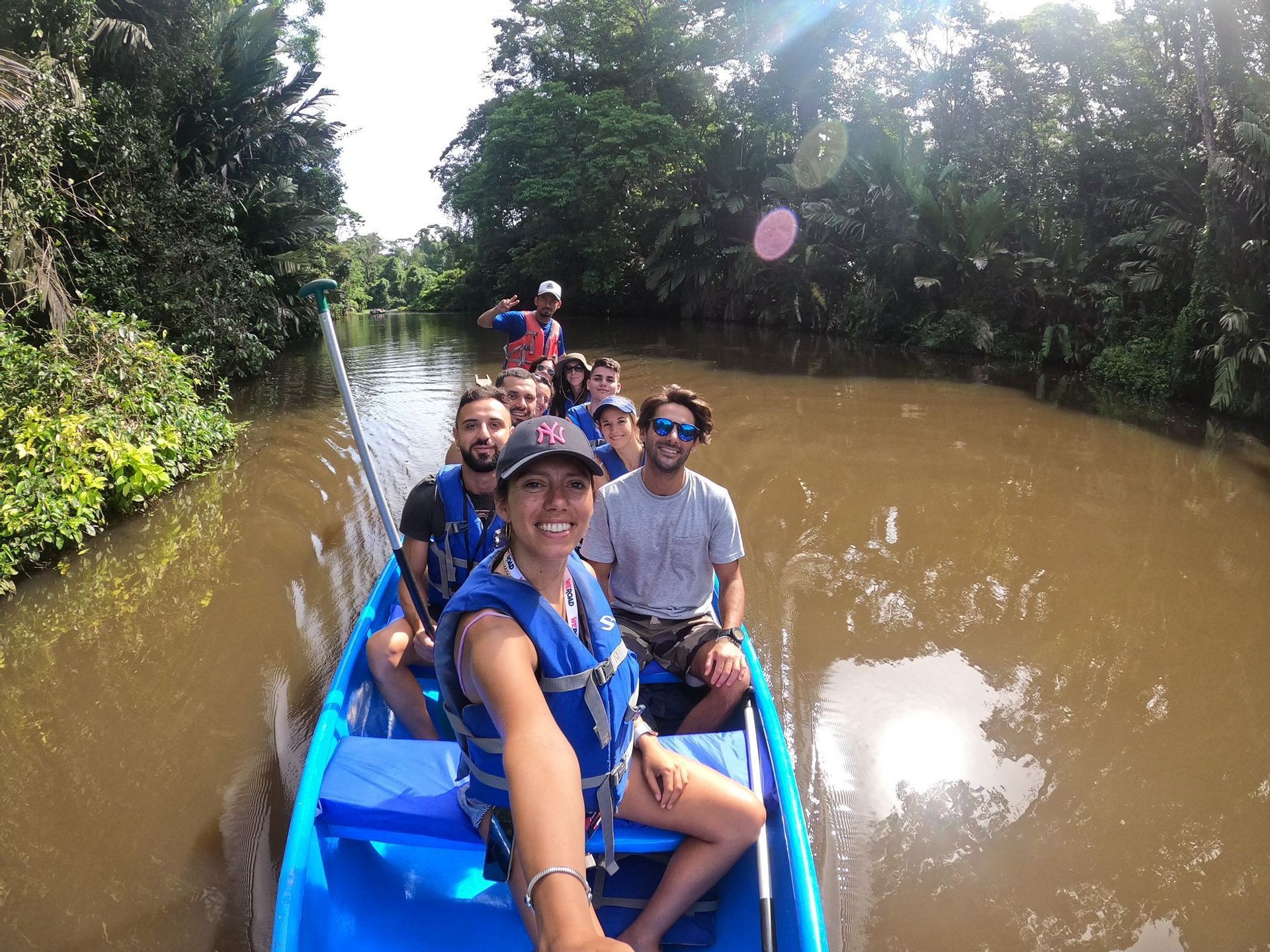 Una donna si scatta un selfie con il suo gruppo WeRoad in una canoa blu su un fiume in una giungla lussureggiante.
