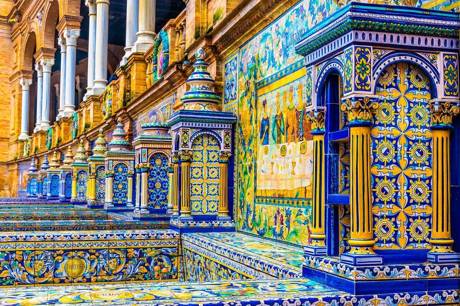 Una fachada ornamentada de un edificio con columnas y bancos, completamente cubierta de azulejos cerámicos de colores azul y amarillo.