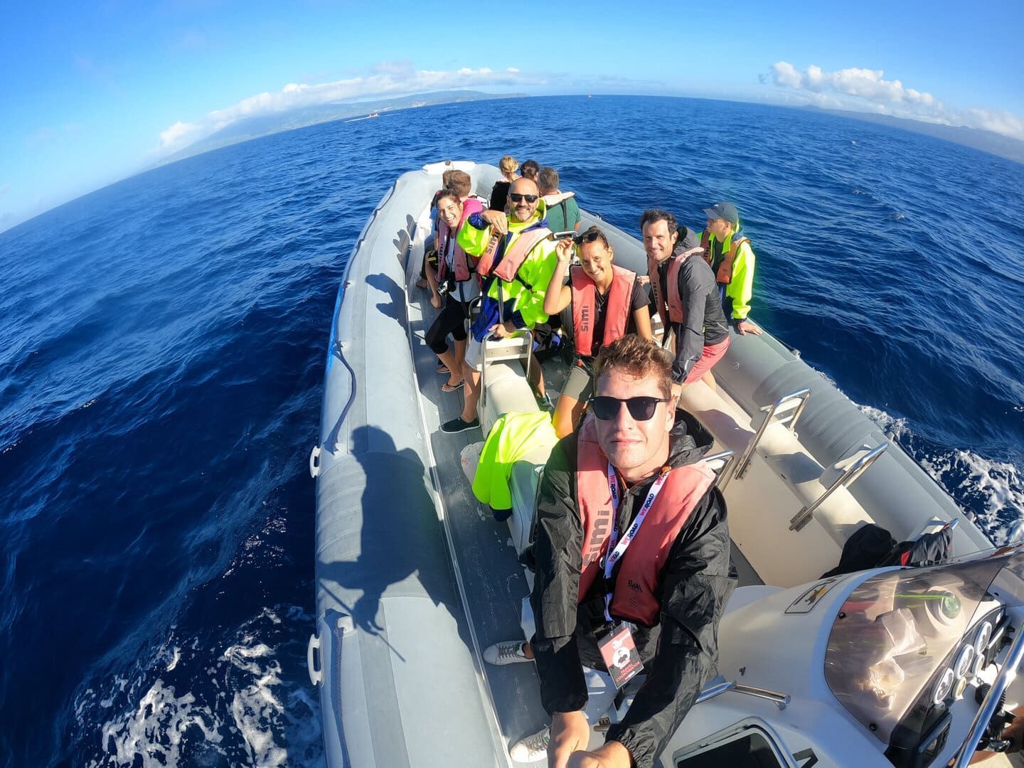 Eine WeRoad-Gruppe lächelt für ein Selfie auf einem Festrumpfschlauchboot auf dem weiten blauen Meer.