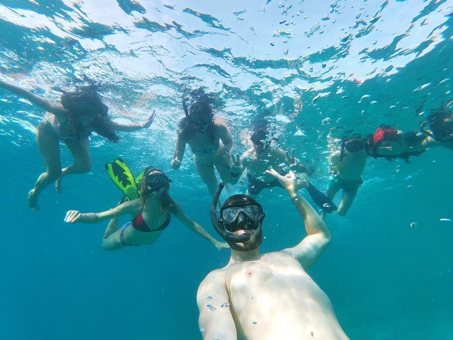 A WeRoad group trip takes a selfie while snorkeling together under the water's surface.