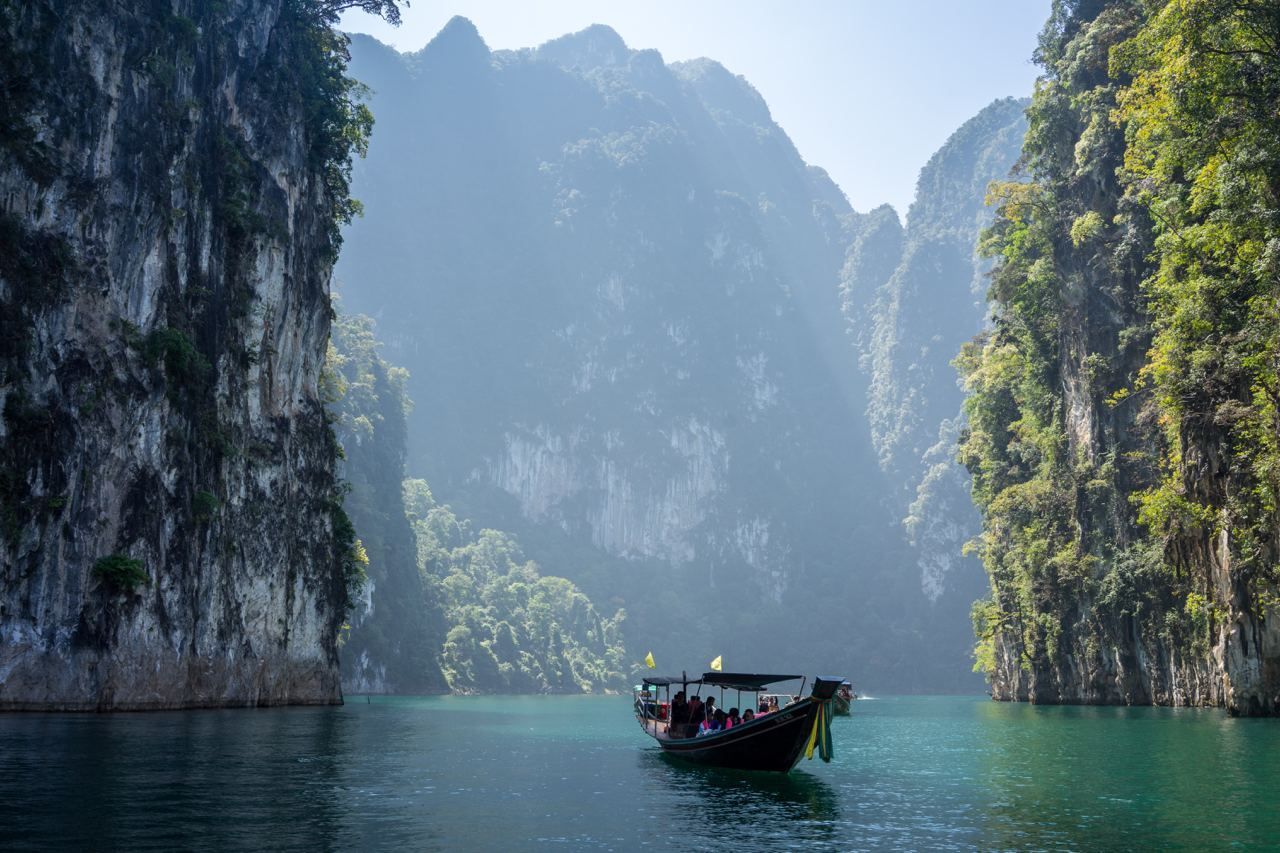 Un voyage de groupe WeRoad en pirogue à longue queue sur des eaux turquoises, entre d'imposantes falaises calcaires verdoyantes.