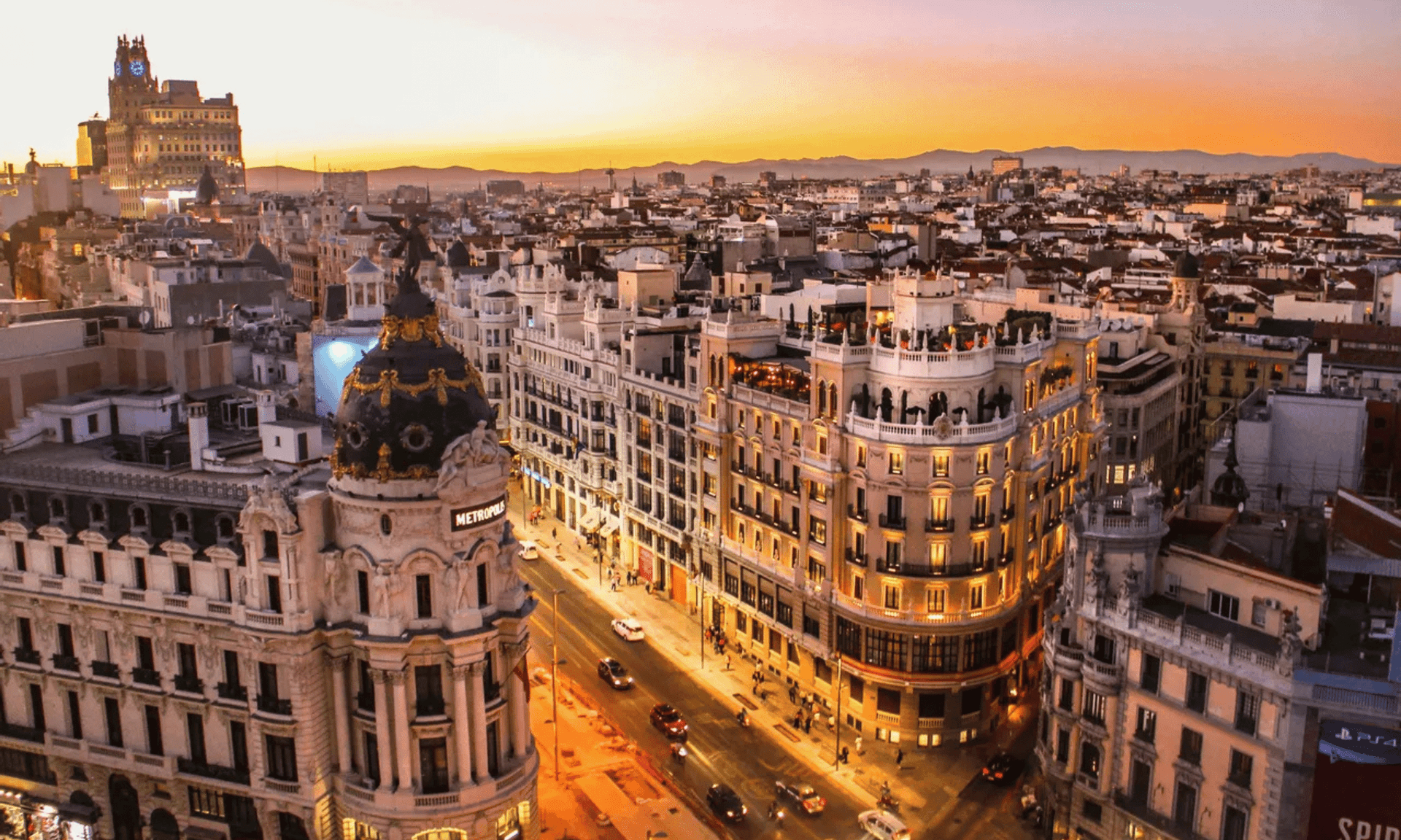 Una vista dall'alto di un paesaggio urbano europeo con un'architettura riccamente decorata, compreso un edificio con cupola prominente, illuminato al tramonto.