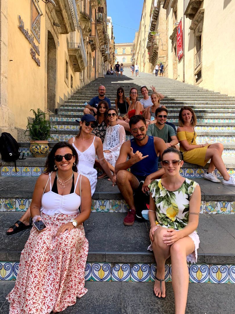 Un voyage de groupe WeRoad posant pour une photo sur un large escalier extérieur avec des carreaux colorés et décoratifs.