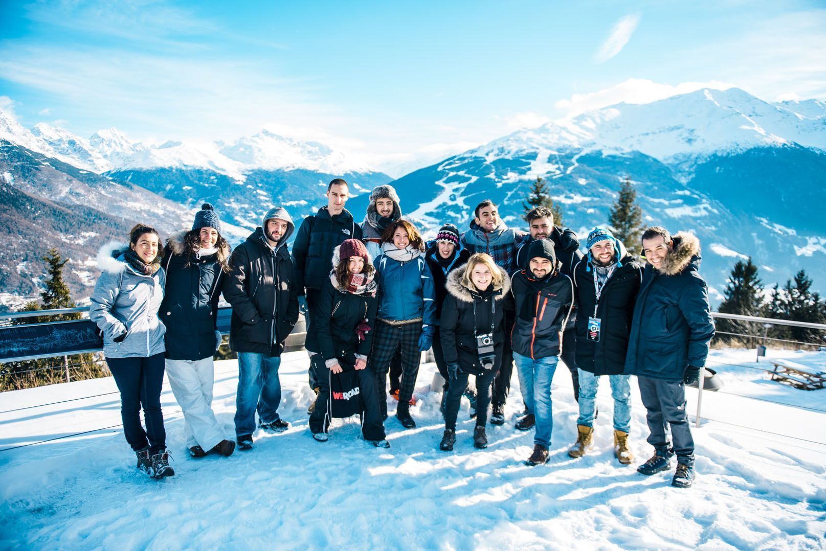 Un viaggio di gruppo WeRoad in posa per una foto sulla neve con lo sfondo di montagne panoramiche innevate.