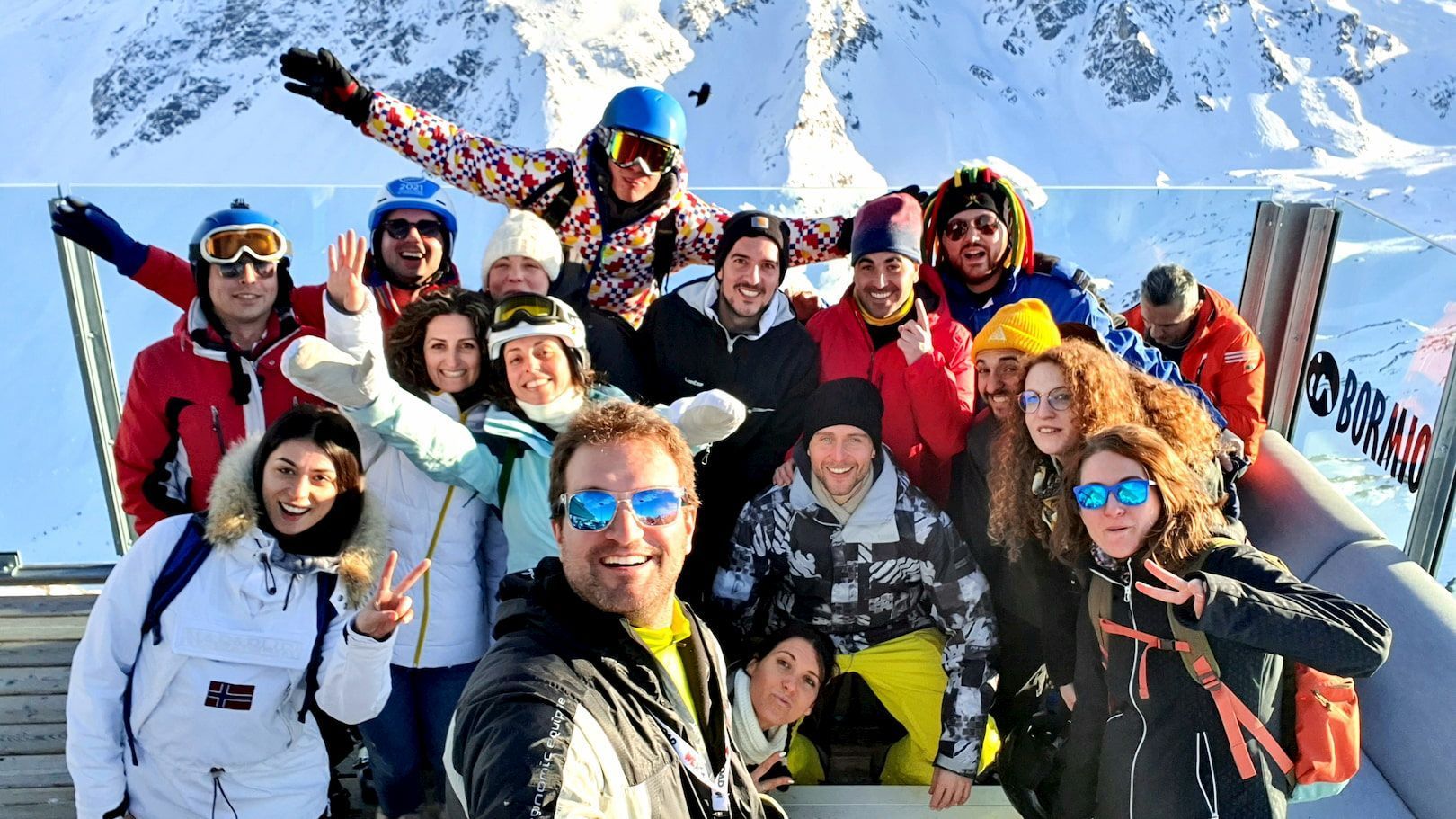 Un gruppo WeRoad in viaggio, con indosso l'attrezzatura da sci invernale, si scatta un selfie di gruppo in una giornata di sole, con montagne innevate sullo sfondo.
