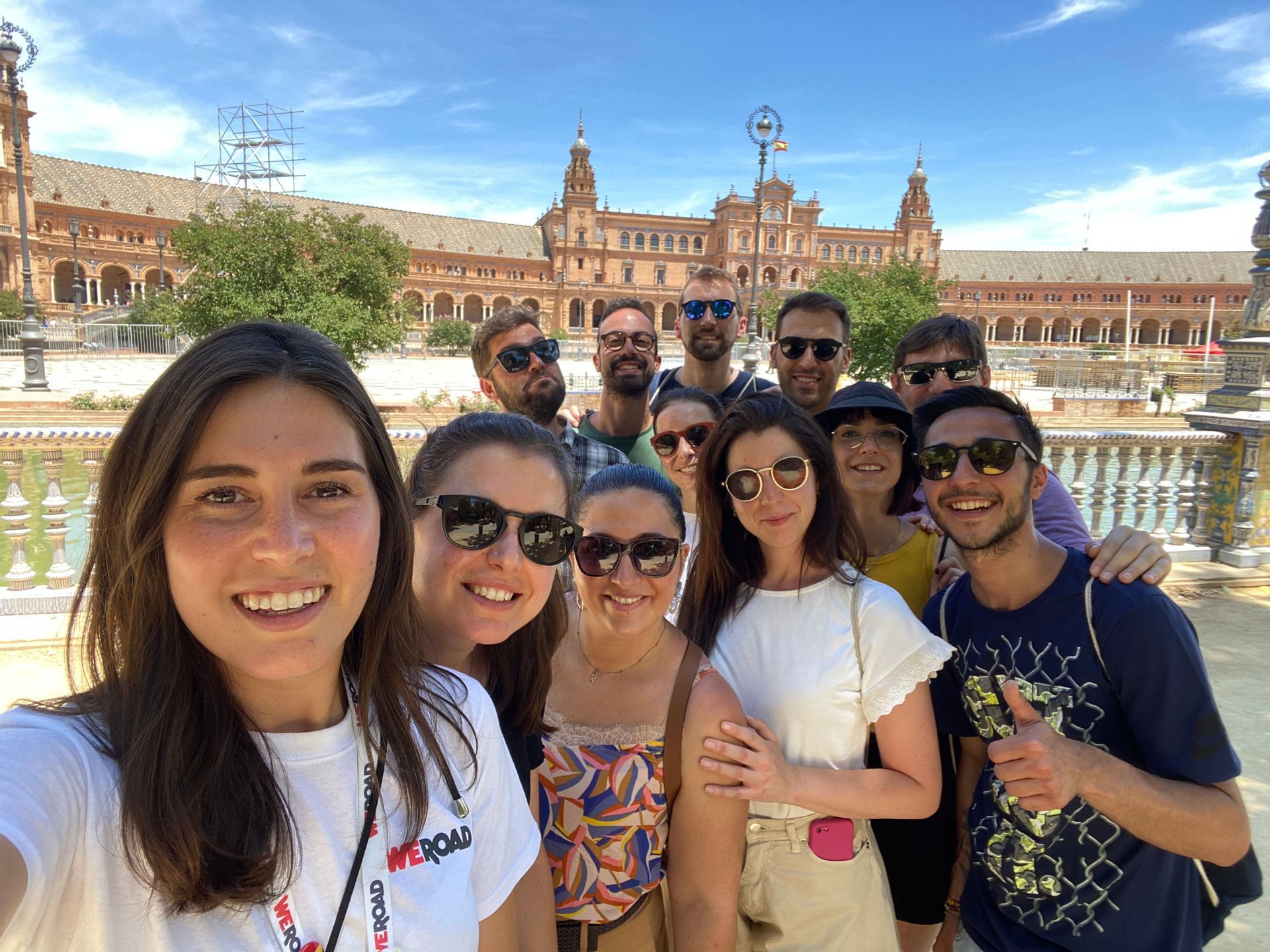Un viaggio di gruppo WeRoad mentre scatta un selfie sorridente all'aperto davanti a un grande edificio storico in una giornata di sole