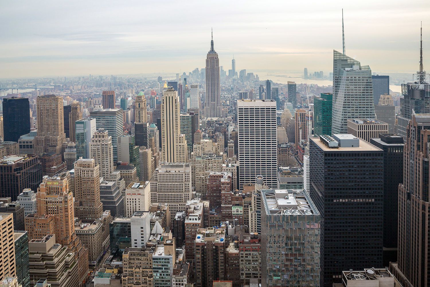 Una veduta aerea di un denso skyline urbano con numerosi grattacieli, tra cui l'Empire State Building, sotto un cielo coperto.