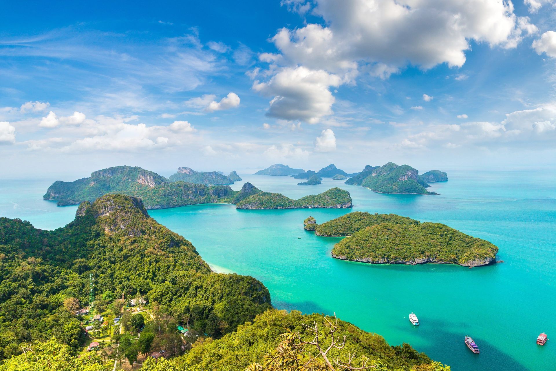 A high-angle view of an archipelago with many lush, green islands sitting in turquoise water under a blue sky with clouds.