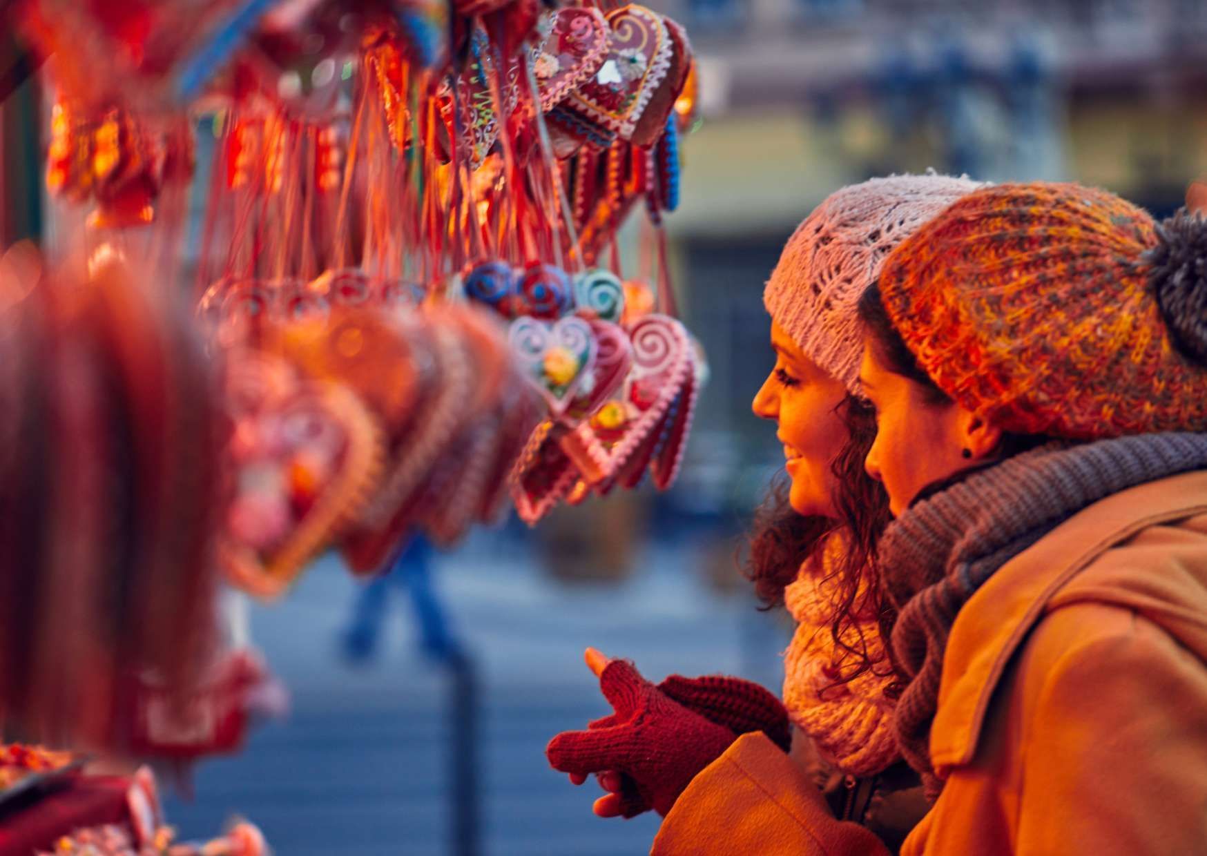 Due donne, con caldi cappelli e sciarpe invernali, osservano biscotti di pan di zenzero colorati a forma di cuore appesi a una bancarella del mercato.