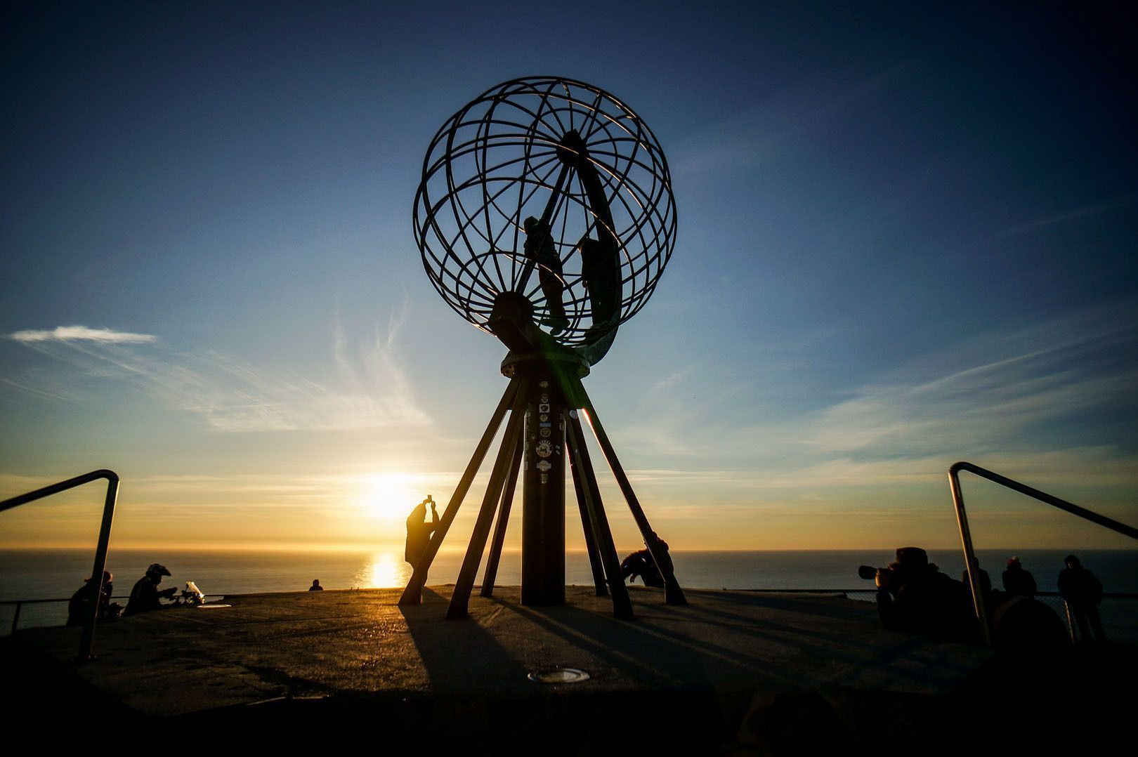 Un viaje en grupo de WeRoad silueteado al atardecer junto a una enorme escultura de globo con vistas al océano.
