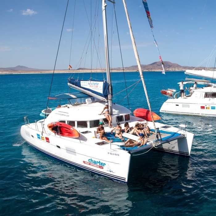 Un viaggio di gruppo WeRoad si rilassa sul ponte di un grande catamarano bianco che naviga su un mare blu calmo.