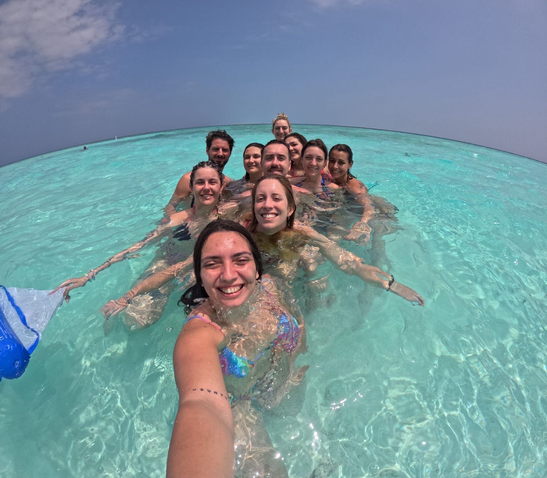 Un gruppo WeRoad si scatta un selfie sorridente mentre nuota in acque oceaniche limpide e turchesi.