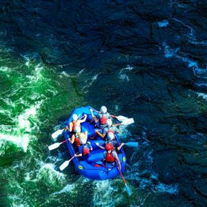 Vista aerea di un gruppo WeRoad su un gommone blu tra rapide fluviali verdi e blu.