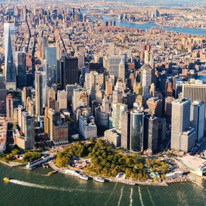 Luftaufnahme der Lower Manhattan Skyline an einem sonnigen Tag, mit dichten, von Flüssen umgebenen Wolkenkratzern.