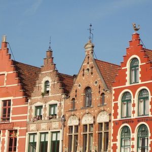 Una hilera de edificios rojos y de ladrillo con gabletes escalonados tradicionales bajo un cielo azul claro.