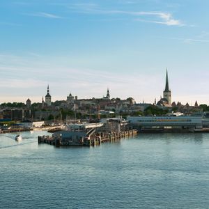 Skyline einer Küstenstadt mit zahlreichen Türmen und historischen Gebäuden, vom Hafen aus über das Wasser mit Booten gesehen.