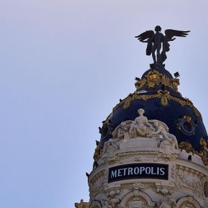 The top of the Metropolis building, featuring a dark dome with gold accents and a winged statue against a clear sky.
