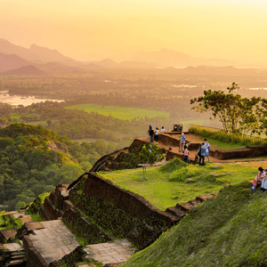 Un viaje en grupo de WeRoad se reúne en un mirador sobre ruinas antiguas, observando un atardecer sobre un valle exuberante con montañas distantes.