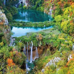 Cascate d'acqua si gettano in laghi turchesi, circondati da una fitta foresta con un fogliame autunnale colorato.