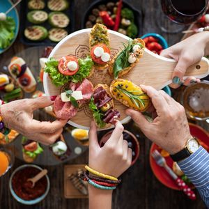 A top-down view of a WeRoad group trip sharing a platter of assorted bruschetta over a rustic table with other appetizers.