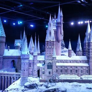 Ein detailliertes Miniaturmodell einer schneebedeckten Fantasieburg, deren zahlreiche Türme und Spitzen von blauen Lichtern illuminiert werden.