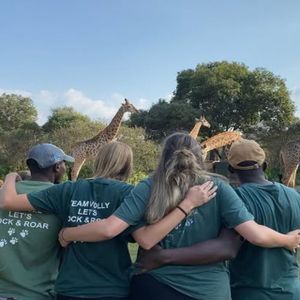 Un voyage de groupe WeRoad, bras dessus bras dessous, observant plusieurs girafes et autruches dans une réserve de savane.