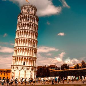 Der Schiefe Turm von Pisa ragt vor einem strahlend blauen Himmel empor, während sich Touristen an einem sonnigen Tag an seinem Fuß versammeln.
