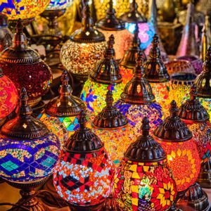 Une collection de lampes mosaïques colorées et illuminées, aux motifs complexes, exposées sur une table.