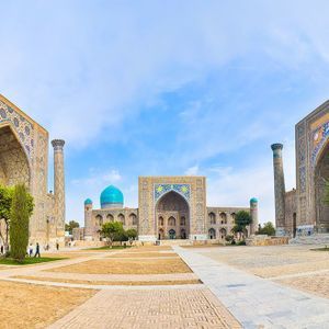 Vista aérea de una plaza histórica con una cúpula turquesa y un minarete alto al amanecer.