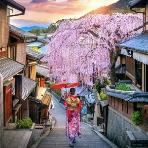 Un guía de grupo de WeRoad visto de espaldas, subiendo escaleras de piedra hacia una gran pagoda japonesa roja con árboles.