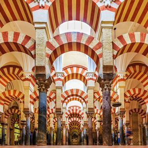 Interior view of a hall with rows of columns supporting distinctive red and beige striped double arches.