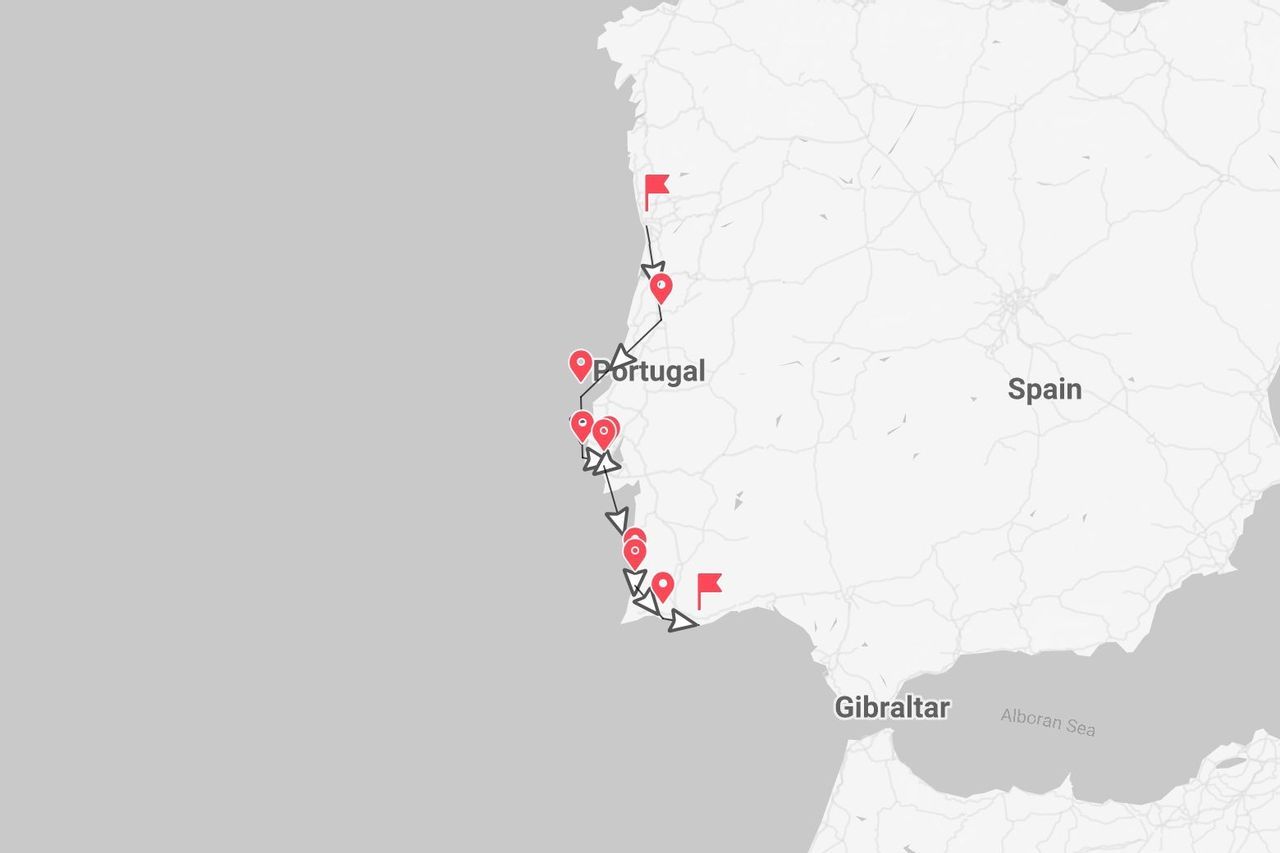 Una mappa che mostra un itinerario di viaggio con puntine e bandierine rosse lungo la costa del Portogallo, con la Spagna visibile a est.