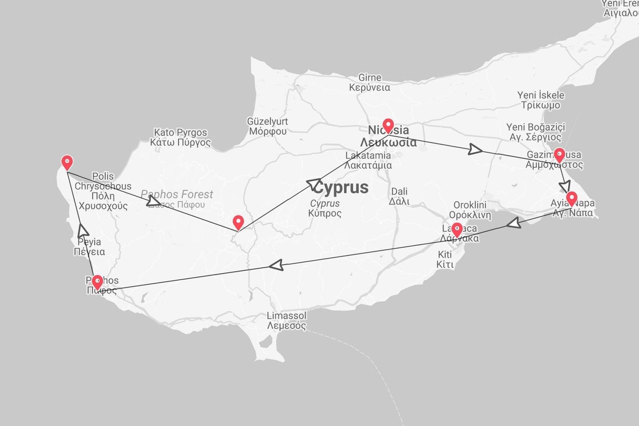 Una mappa in scala di grigi di Cipro con un itinerario di viaggio contrassegnato da puntine rosse e una linea nera che collega città come Paphos, Nicosia e Larnaca.