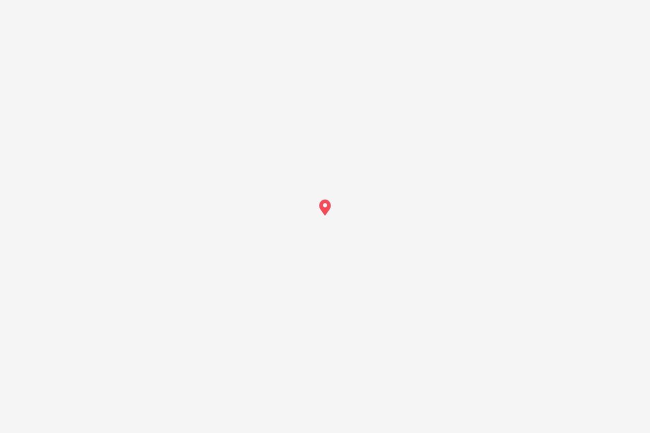 Un pequeño ícono de marcador de mapa rojo con un punto blanco en el centro, sobre un fondo gris claro.