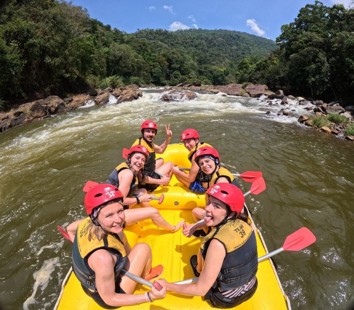 Eine WeRoad-Gruppe mit roten Helmen und Schwimmwesten lächelt während eines Rafting-Ausflugs auf einem gelben Schlauchboot für ein Foto.