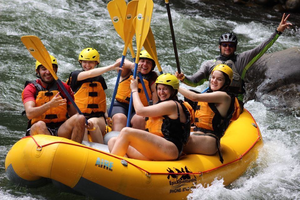 Un grupo de WeRoad sonríe mientras hace rafting en un río de aguas rápidas, llevando cascos y chalecos salvavidas.