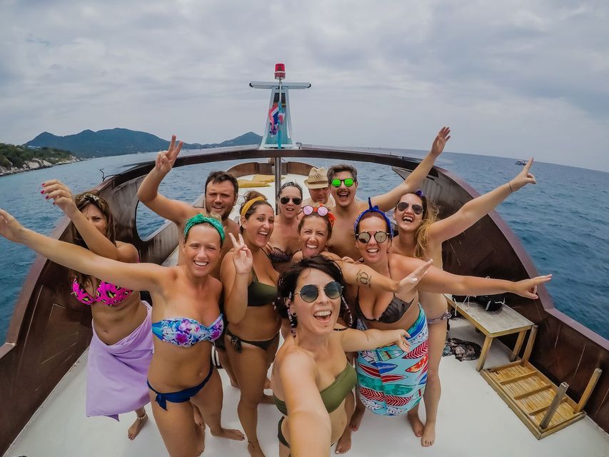 Eine WeRoad-Gruppenreise von Personen in Badekleidung, die auf dem Deck eines Boots auf See für ein Selfie posieren.