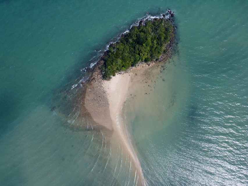 Luftaufnahme einer kleinen, bewaldeten Insel mit langer Sandbank im türkisfarbenen Meer.