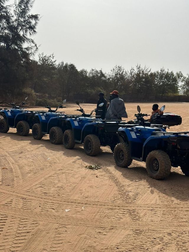 Una fila de quads azules aparcados en una pista de arena, con un grupo de viaje de WeRoad preparándose para una excursión.