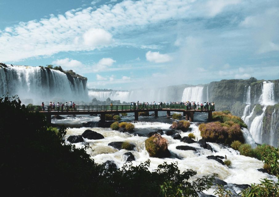 Un viaggio di gruppo WeRoad su una piattaforma panoramica sopra un fiume impetuoso, con una vista mozzafiato su cascate imponenti.