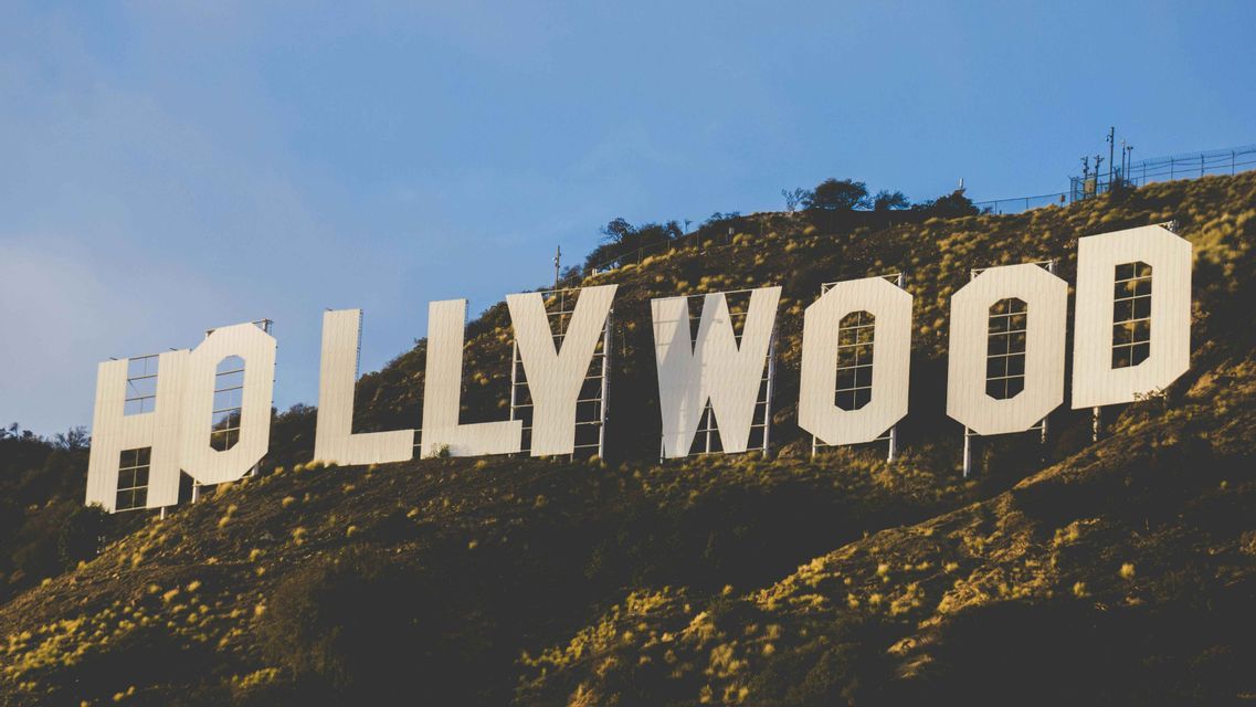La grande insegna bianca di Hollywood si trova su una collina erbosa sotto un cielo azzurro e limpido.