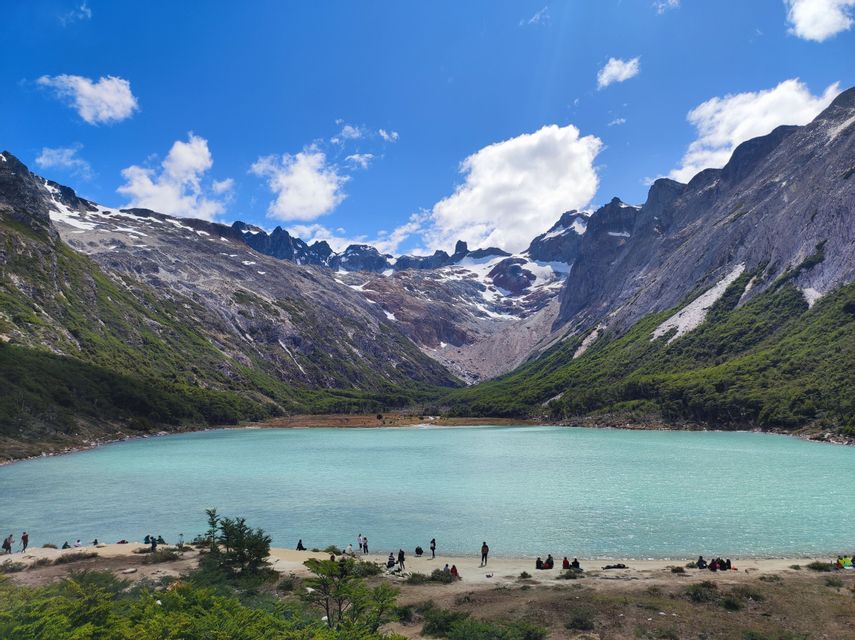 Un viaggio di gruppo WeRoad in riva a un lago alpino turchese circondato da montagne innevate.