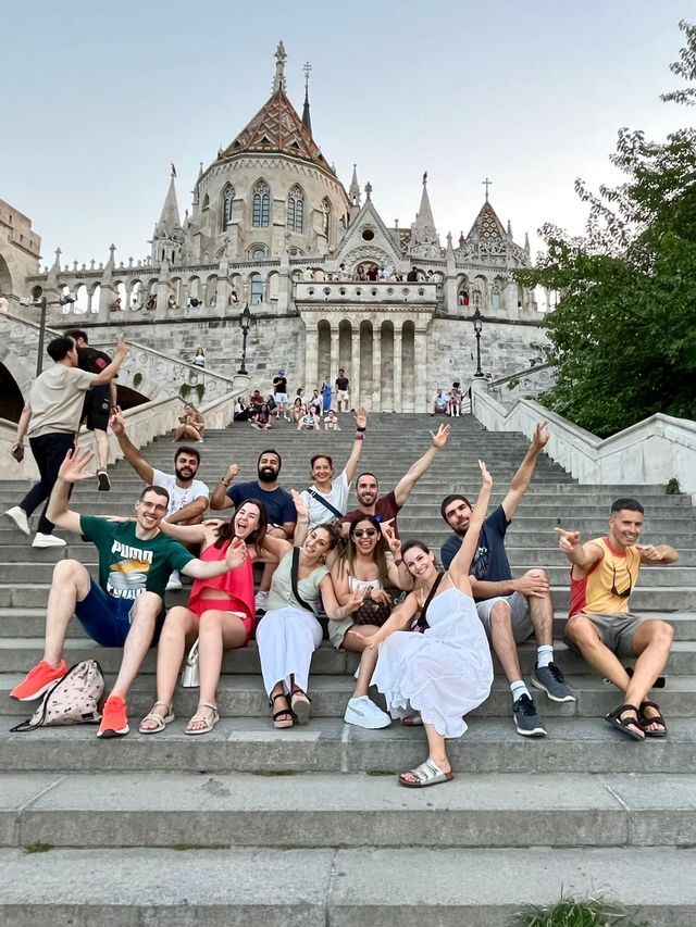 Un grupo de WeRoad posa sonriente para una foto en una amplia escalinata de piedra frente a un gran edificio ornamentado.